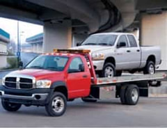 a picture for a towing truck carrying a pickup car under a bridge