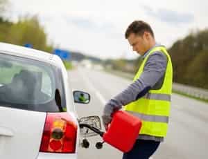 a man in yellow vest in a highway fueling an out of gas car for roadside assistance